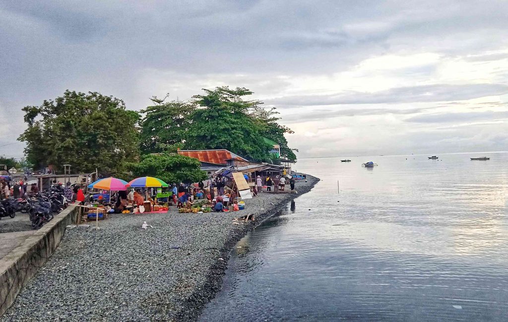 Suasana Pasar Ikan Ampana di tepi pantai, tempat warga menjual hasil laut dan pertanian segar. Tradisi berdagang yang menyatu dengan alam ini menjadi denyut nadi ekonomi dan budaya pesisir di Sulawesi Tengah.