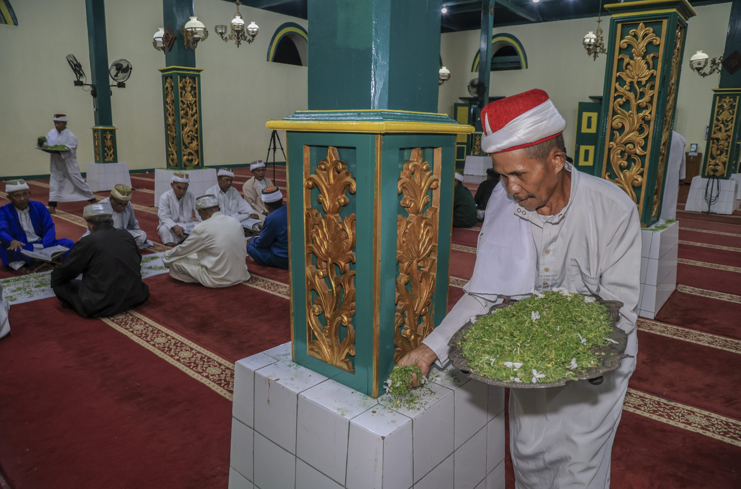 Seroang modim (pengurus masjid) menabur daun pandan ke tiang masjid  saat tradisi khataman tadarus Al Quran di Masjid Kesultanan Ternate, Maluku Utara, Jumat (27/2/2026). Tradisi khataman Al Quran yang pertama di malam ke-10 Ramadhan itu digelar Pengurus Masjid Kesultanan Ternate yang terdiri dari imam, khatib dan modim karena telah menyelesaikan bacaan Al Quran 30 juz mulai pada awal Ramadhan untuk meningkatkan amal ibadah dan memohon ampunan dari Allah SWT sekaligus mempertahankan tradisi lokal bernuansa islami dengan melestarikan kearifan lokal yang diwariskan para leluhur mereka.